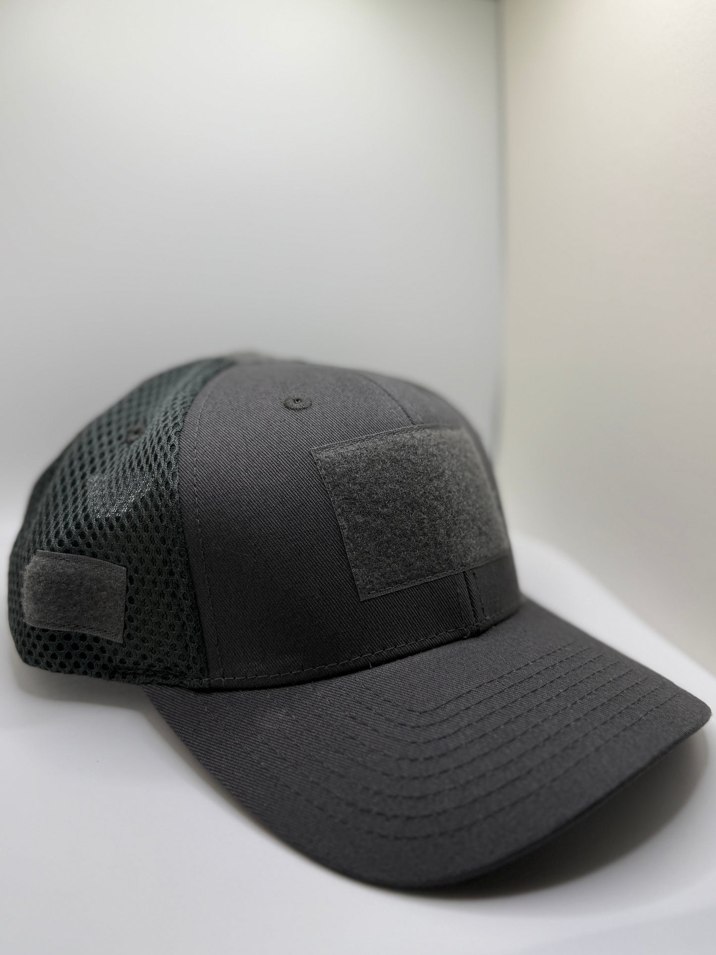 Black tactical cap with mesh back on a white surface