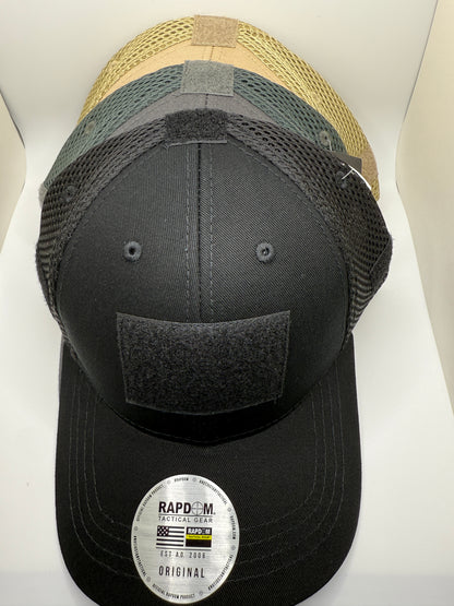 Three baseball caps of different colors stacked on a white surface with a visible brand label.